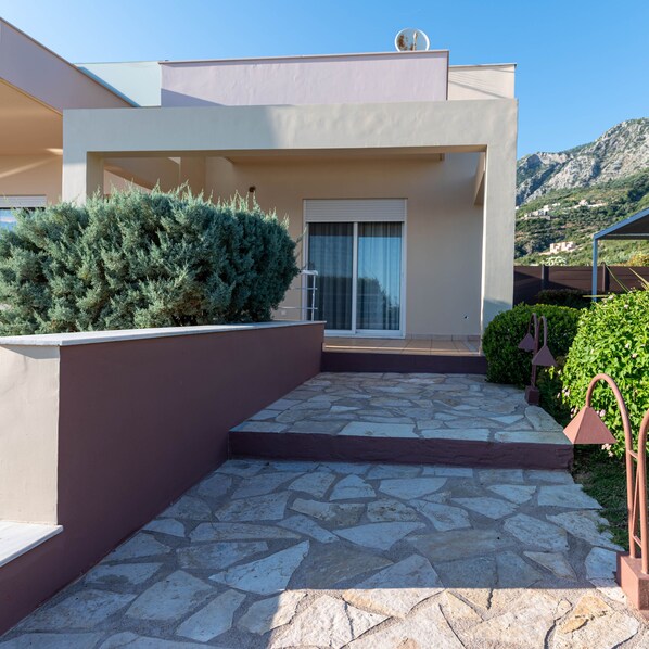 Un bâtiment moderne doté d’un patio carrelé, d’un grand arbuste et offrant une vue sur la montagne.