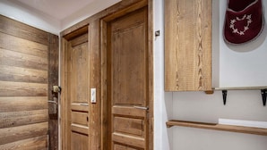 A wooden door with a handle and a lock, a white wall with a shelf, and a red object on the wall.