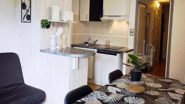 A compact kitchen with a built-in dishwasher, a small countertop, and a dining area with a table and chairs.