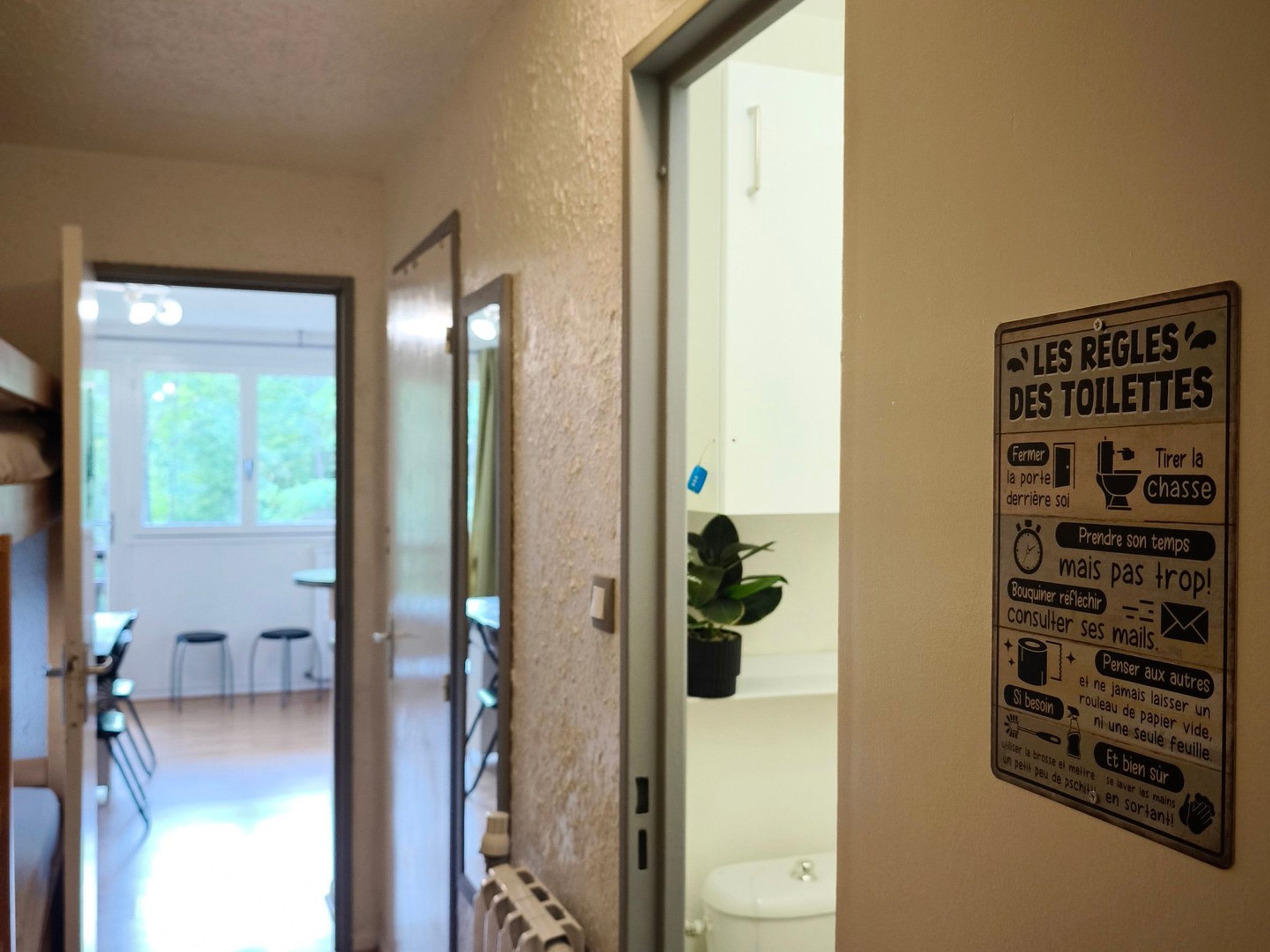 A hallway with a sign detailing bathroom rules in French.