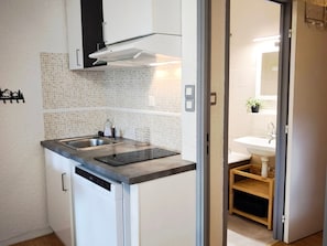 Cozinha compacta com lava-louças embutida, pia de aço inoxidável e painel de azulejos.