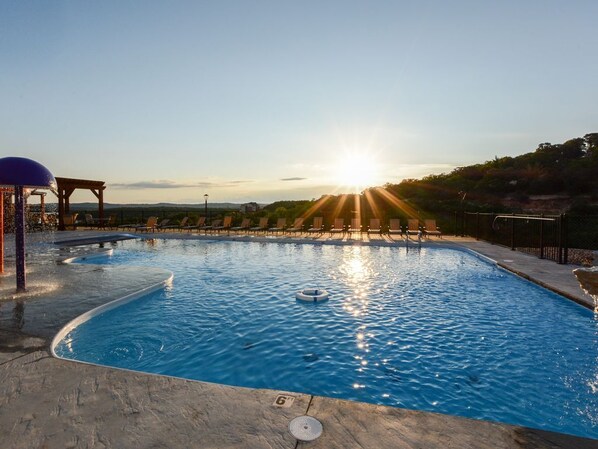 Relax by the serene pool surrounded by lush trees and a city view.