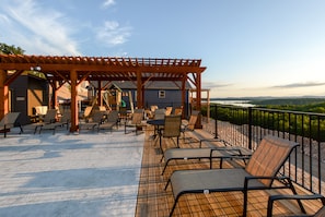 Relax in a shaded patio area with lounge chairs and a table, surrounded by a scenic view of water and distant landscape.
