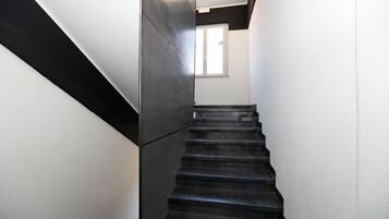A modern staircase with a black and white color scheme, leading to a room with a window.