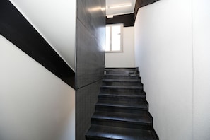 A modern staircase with a black and white color scheme, leading to a room with a window. - Hotello (Trieste)