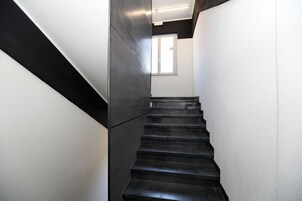 Una moderna scala con schema colori bianco e nero che conduce a una stanza con una finestra.