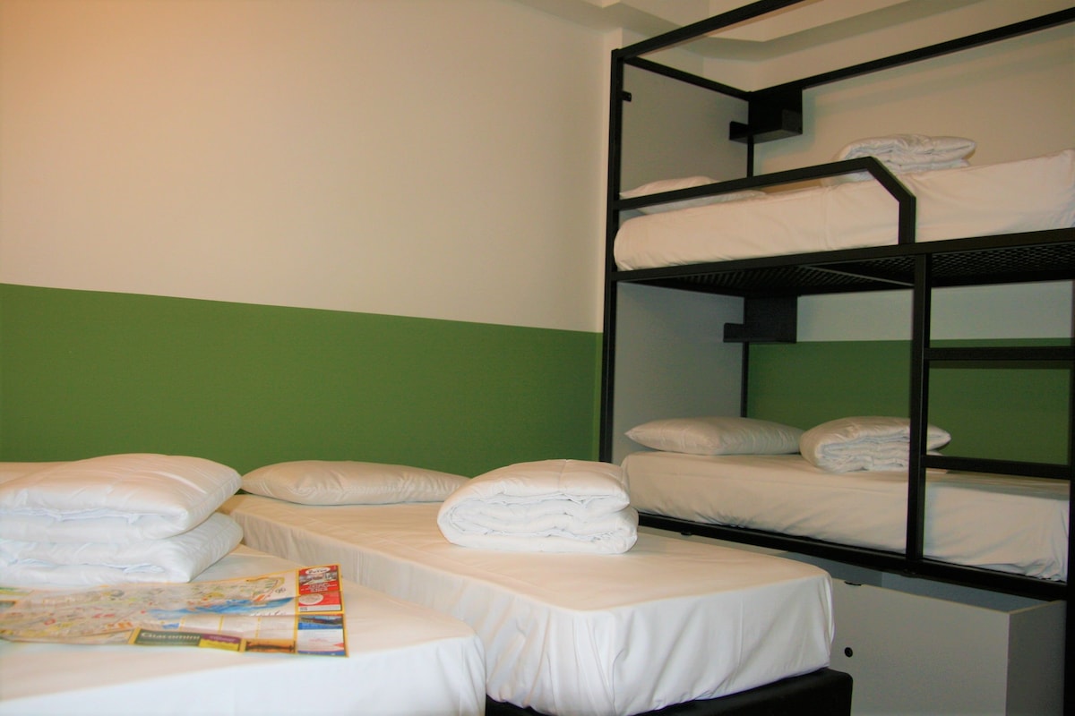 A bunk bed room with green walls and white bedding.