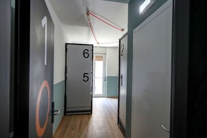 Un corridoio con porte numerate, un lampadario e vista su un balcone.