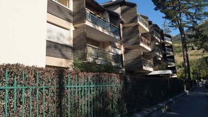 A multi-story residential building with balconies, a green fence, and a clear sky. - Quiet T2 apartment in Barcelonnette, city center (Barcelonnette)