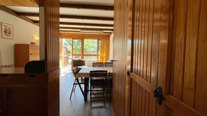 A wooden interior with a dining area, a kitchen, and a large window providing natural light.