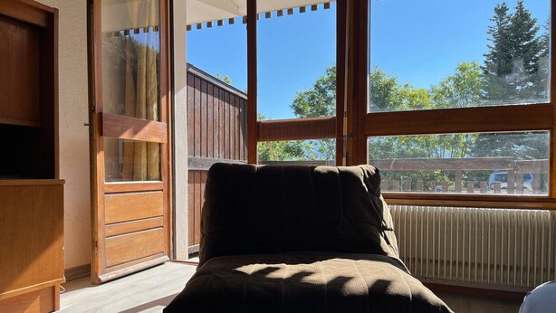A room with a large window, a wooden chair, and a radiator.