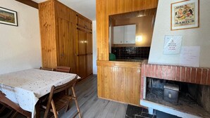 A compact kitchen with wooden cabinets, a dining table, and a fireplace.