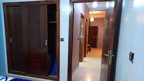 A bedroom with a wardrobe, a bed, and a hallway leading to another room. - Residence Annaser 3 Agadir (Hay Essalam,Agadir)