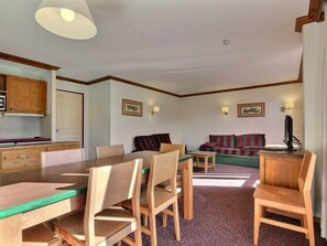 Um quarto com uma mesa de jantar, cadeiras, um sofá e uma televisão.