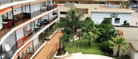 A multi-story hotel with a swimming pool, balconies, and a garden area.