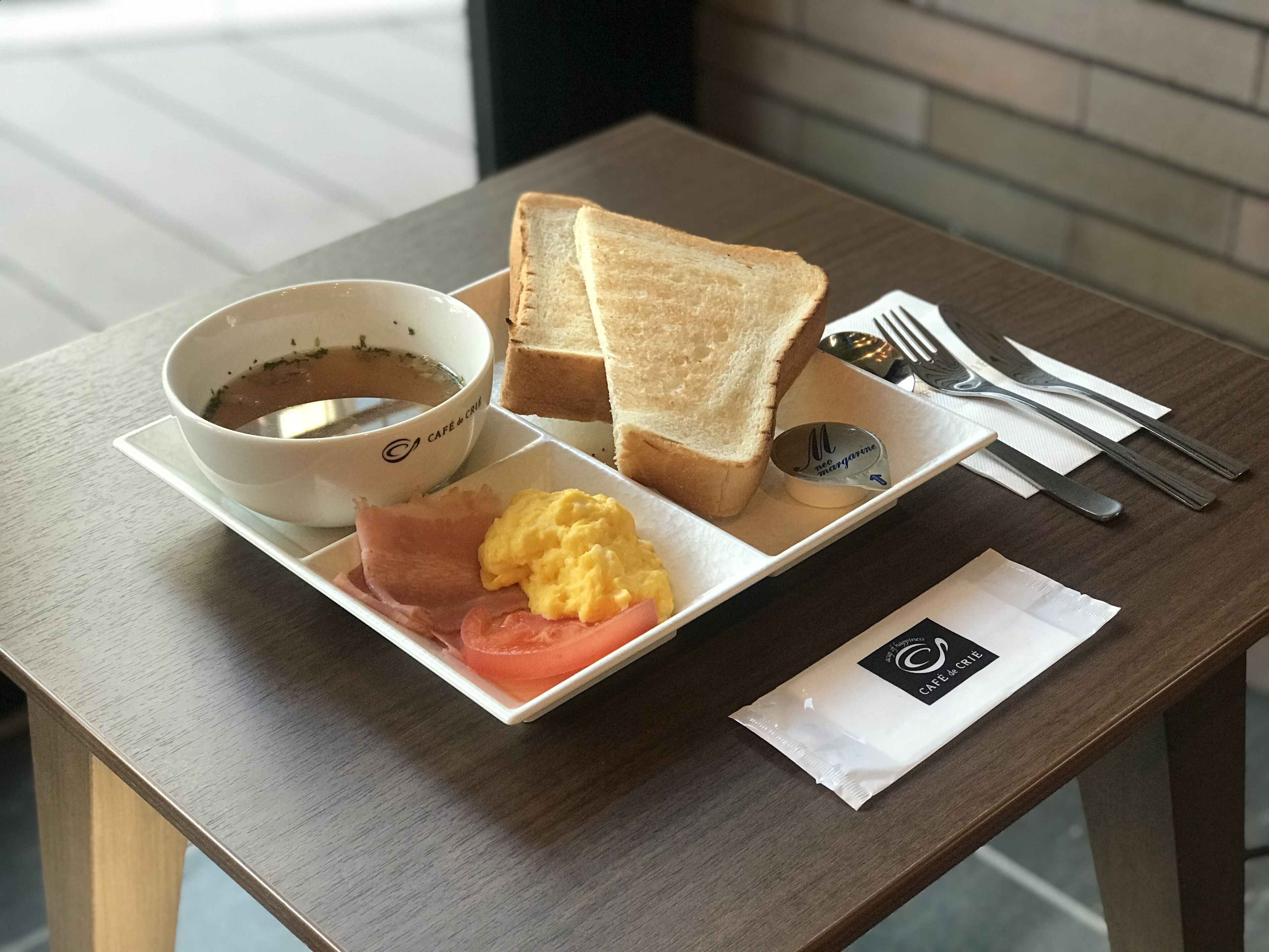 A breakfast tray with toast, scrambled eggs, ham, and a cup of coffee.