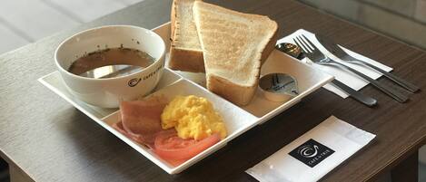 A breakfast tray with toast, scrambled eggs, ham, and a cup of coffee.