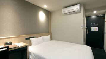 Una habitación de hotel con cama, mesita de noche y aire acondicionado.