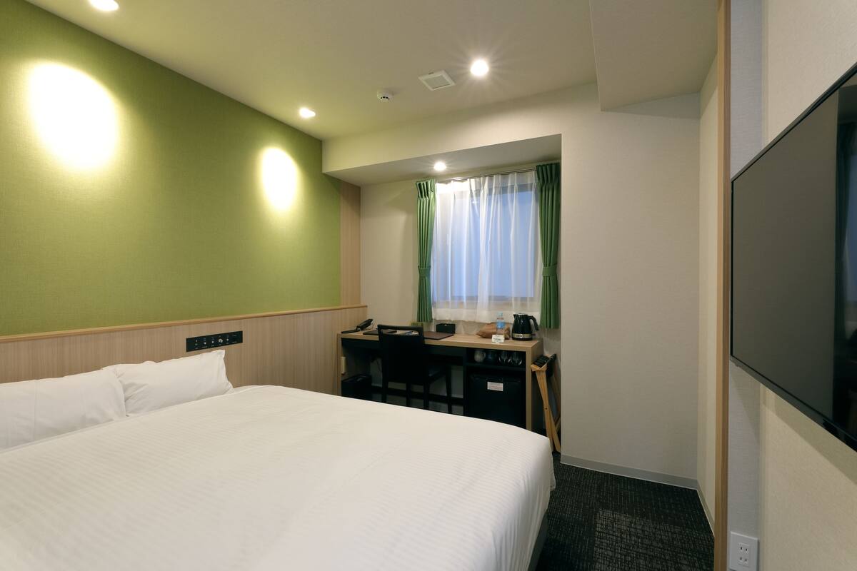 A hotel room with a bed, desk, and TV.