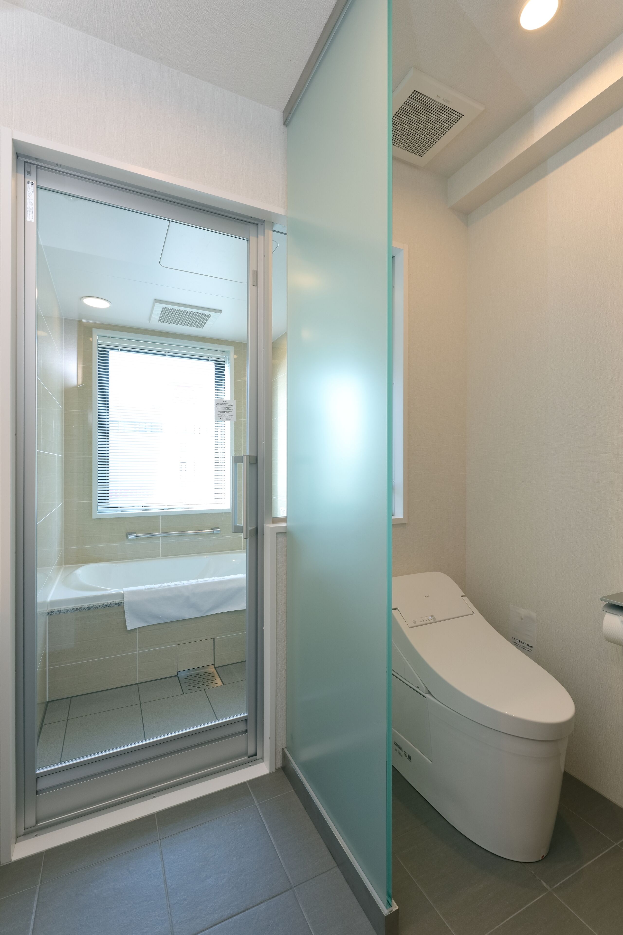 A modern bathroom with a glass shower enclosure, a toilet, and a sink.