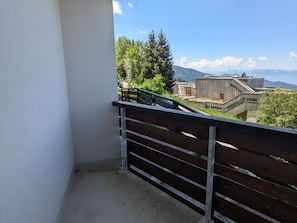 Un balcon doté d’une rambarde en métal, donnant sur un quartier résidentiel avec des maisons et des arbres.