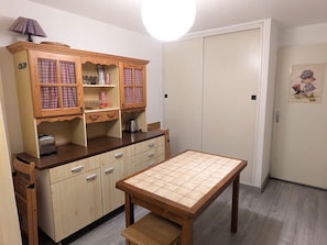 A compact kitchen with wooden cabinets, a table, and a bench.