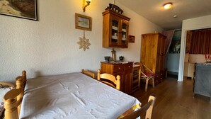 A cozy room with a bed, wooden furniture, a cabinet, and a painting on the wall. - Mini T2 Duplex in Barcelonnette, perfect for 4 (Barcelonnette)
