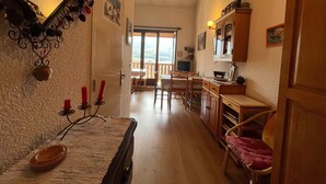 A cozy kitchen with wooden cabinets, a dining table, and a view to the outside. - Mini T2 Duplex in Barcelonnette, perfect for 4 (Barcelonnette)