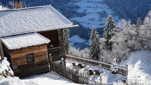 A wooden cabin with a balcony, surrounded by snow-covered trees and a mountain view. - Holiday Home "Bergsuite" with Mountain View, Balcony, Garden & Wi-Fi (St.Martin in Passeier)