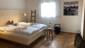 Une chambre avec un lit en bois, une échelle, une petite table, une lanterne et une affiche accrochée au mur.