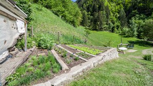 A garden with raised beds, a stone wall, and a wooden structure. - Apartment “Familienwohnung” in “Schildhof Ebion” with Mountain View, Wi-Fi & Garden (St. Leonhard Passeier)