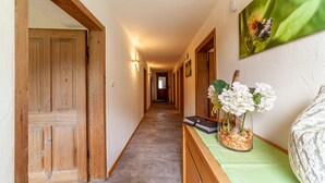A hallway with wooden doors, a green table with a vase, and a framed picture on the wall. - Apartment “Familienwohnung” in “Schildhof Ebion” with Mountain View, Wi-Fi & Garden (St. Leonhard Passeier)