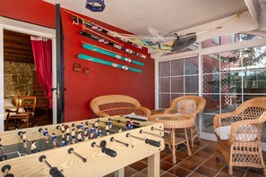 A room with a foosball table, wicker chairs, and a wall with skis.