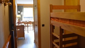 A room with a bunk bed, a desk with a lamp, and a view of a balcony. - Ski-In/Ski-Out Studio for 4 in Méribel, Pool Access, Near Shops & Bus Stop (Méribel)