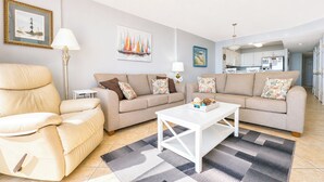 Ein Wohnzimmer mit einer Couch, einem Sessel, einem Couchtisch und einem Teppich.