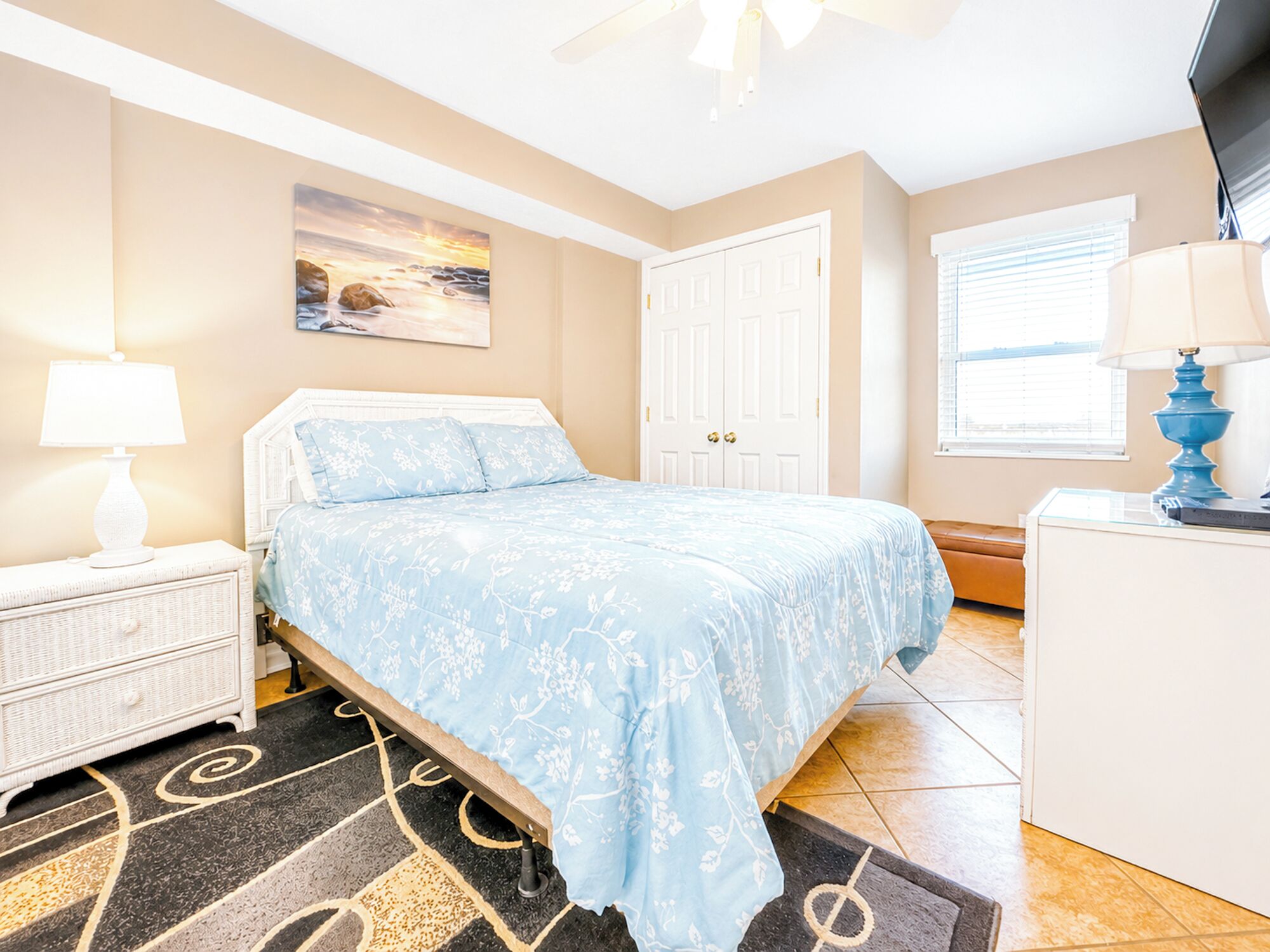A bedroom with a bed, nightstand, dresser, and a painting on the wall.