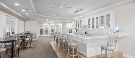 A spacious kitchen with a central island, white cabinetry, and a dining area with chairs.