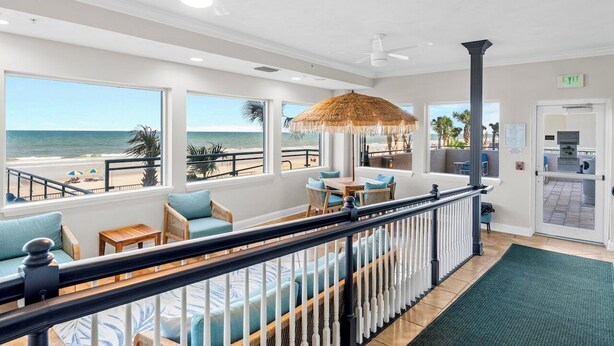 Un restaurant situé en bord de mer, avec une terrasse, un parasol en chaume et une vue sur l’océan.