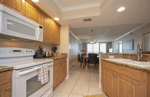 Una cocina con armarios de madera, microondas, estufa y comedor con mesa y sillas.