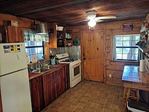 Une cuisine rustique avec des meubles de rangement en bois, un poêle et un évier.