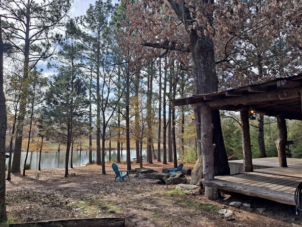 Un chalet au bord du lac, doté d’une terrasse, de deux chaises et d’un espace abrité.