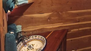 Een houten cabin interieur met een wastafel, een handdoekhouder en een bordje met de tekst 'wash up BUTTERCUP'.