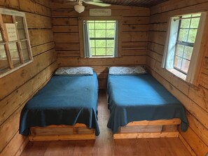 Une cabane avec deux lits en bois, une fenêtre et un panneau accroché au mur.