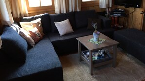 Uma sala de estar acolhedora com um sofá seccional, uma mesa de centro e uma televisão.