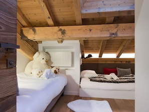 A cozy attic bedroom with two beds, wooden beams, a white radiator, and a teddy bear on one bed. - Stunning contemporary apartment in Courchevel 1850, 3 bedrooms, sauna, parking (Courchevel 1850)