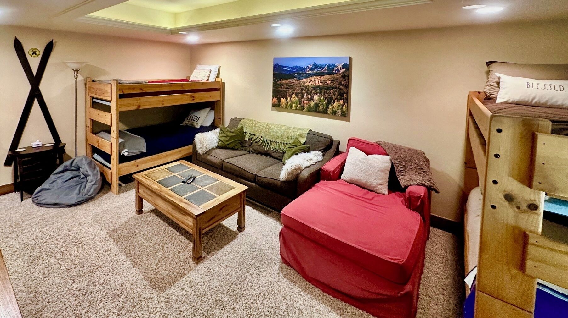 A cozy room with a bunk bed, a red sofa, a small table, and a wooden cabinet.