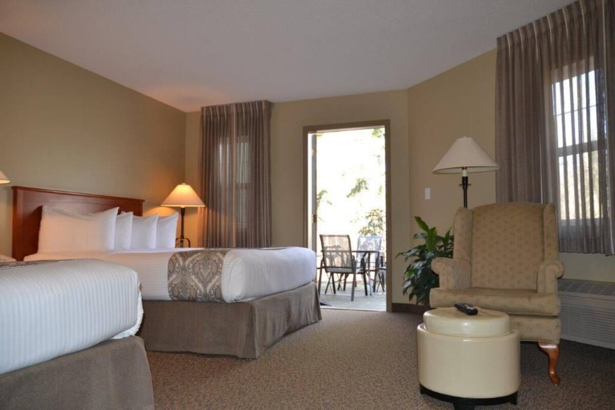 Une chambre d’hôtel avec deux lits, une chaise, une table et une lampe.