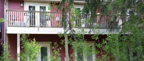 Ein zweistöckiges Gebäude mit Balkon, überdachter Veranda und kleinem Garten.