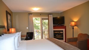 Ein Hotelzimmer mit einem großen Bett, einem Fernseher, einem Kamin und einem Balkon mit Vorhängen.