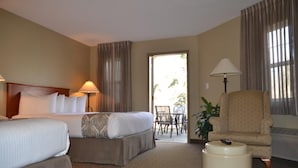 Ein Hotelzimmer mit zwei Betten, einem Sessel, einem Tisch und einer Lampe.